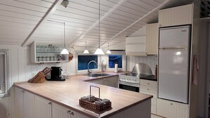 A modern kitchen with white cabinetry, a central island, a built-in stove, and a refrigerator. - Super cozy holiday home in Marielyst (Væggerløse)