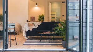 Un salón acogedor con un sofá negro, una mesita y una planta en maceta.