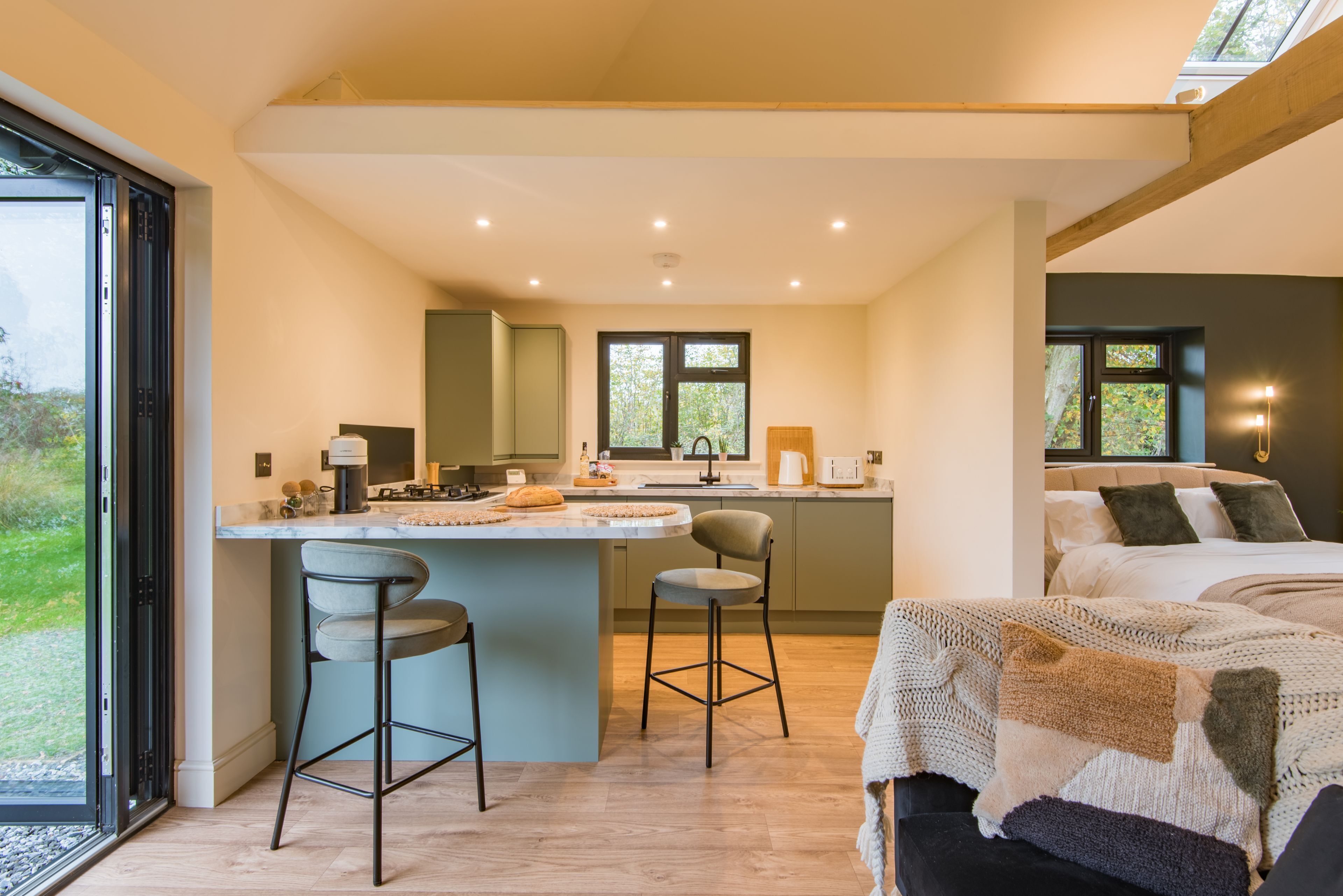Een moderne keuken met een centraal eiland, barkrukken en een eethoek.