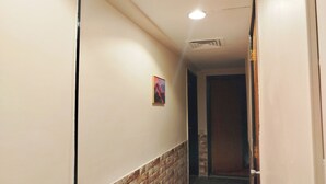 A hallway with a brick accent wall, a painting, and a door at the end. - Garden City Apartment in Downtown Cairo (Cairo)