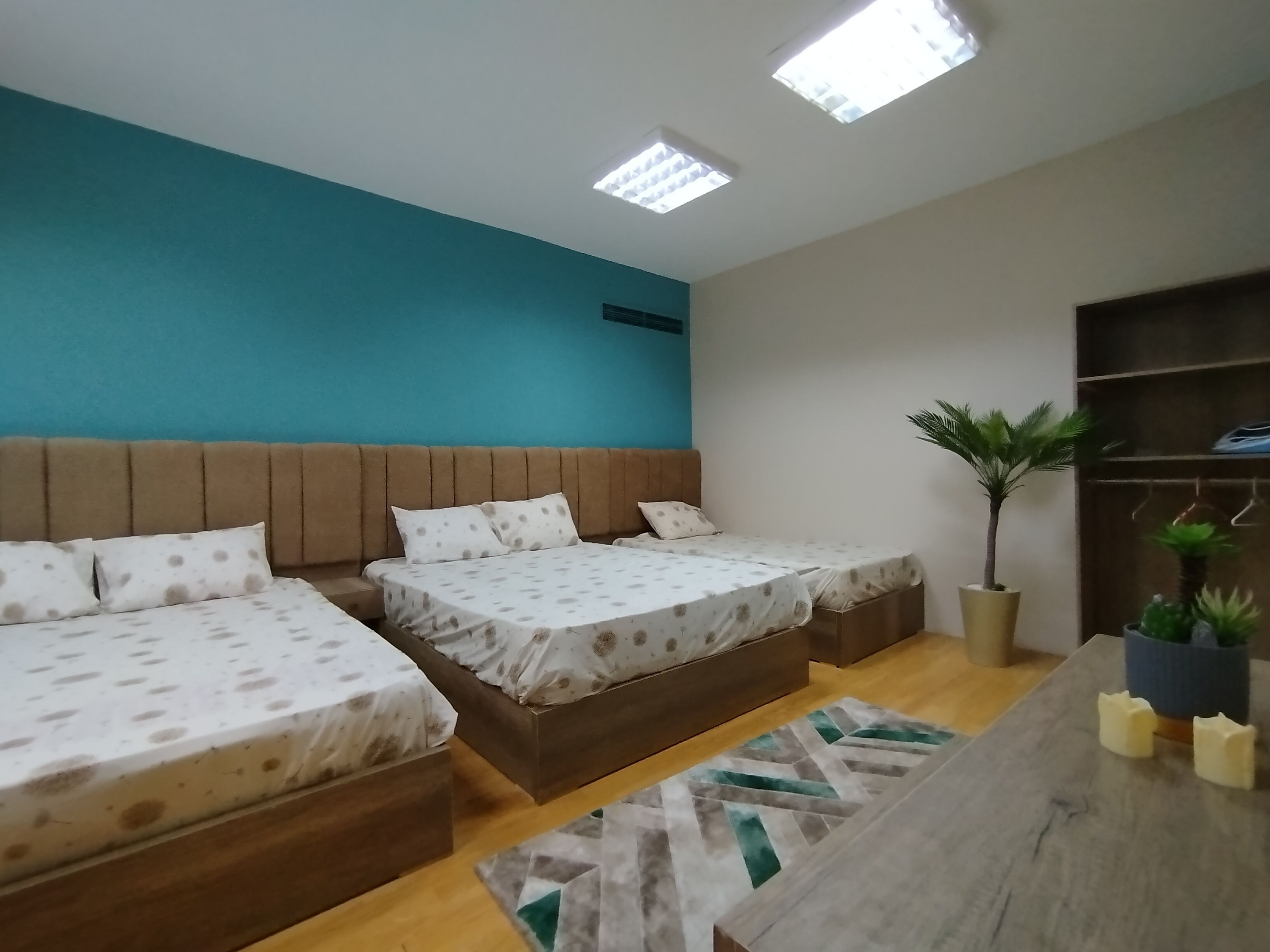 A bedroom with two beds, a wooden headboard, a small potted plant, and a wooden table with candles.
