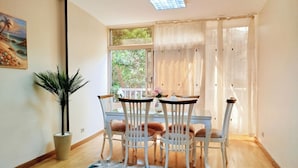 A dining area with a table and chairs, a potted plant, and a painting on the wall. - Garden City Apartment in Downtown Cairo (Cairo)