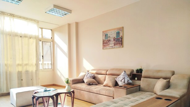 A modern living room with a sofa, ottoman, and a small table. - Garden City Apartment in Downtown Cairo (Cairo)