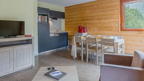 Ett kompakt bostadsutrymme med ett litet kök, en matplats och en soffa.
