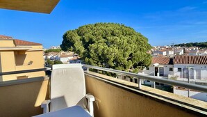 A balcony with a view of a large tree and a town in the background.