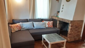 Un salon avec un canapé d’angle, une petite table et une cheminée en briques.