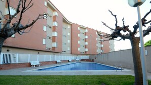 A swimming pool with a white fence, benches, and a tree in a courtyard. - TERRASSA DEL MAR 6-1-B (L'Escala)