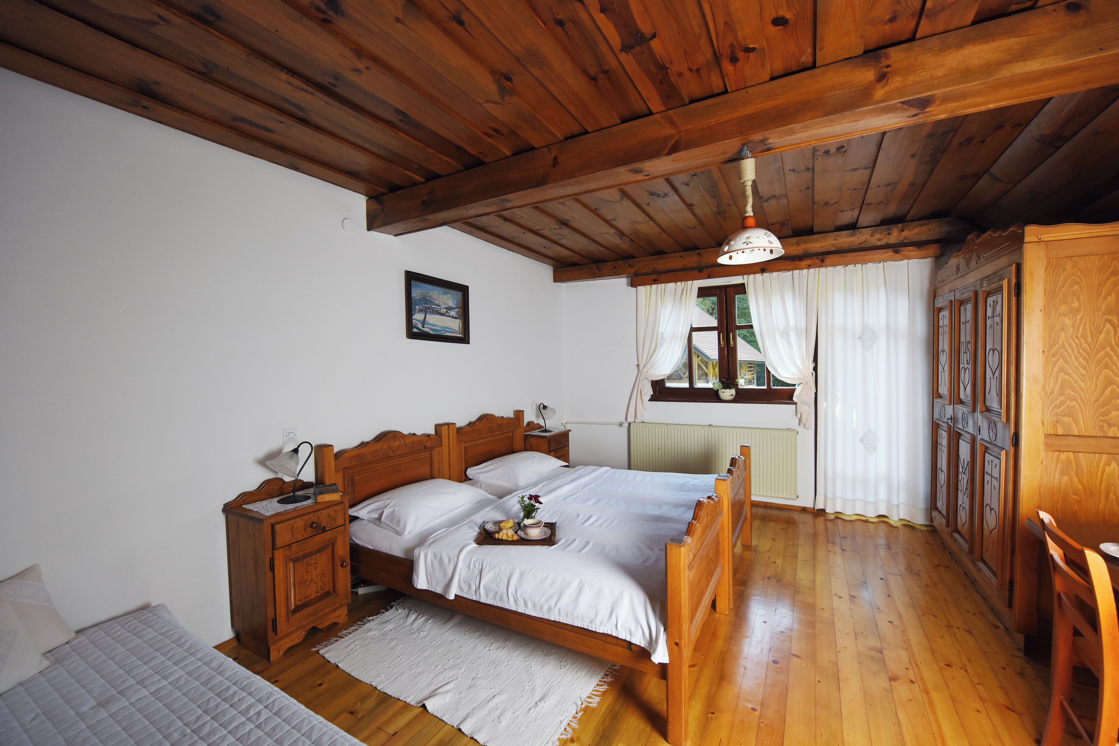 Un dormitorio de madera con cama, mesitas de noche y una ventana con cortinas.