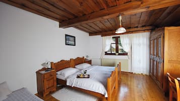 Un dormitorio de madera con cama, mesitas de noche y una ventana con cortinas.
