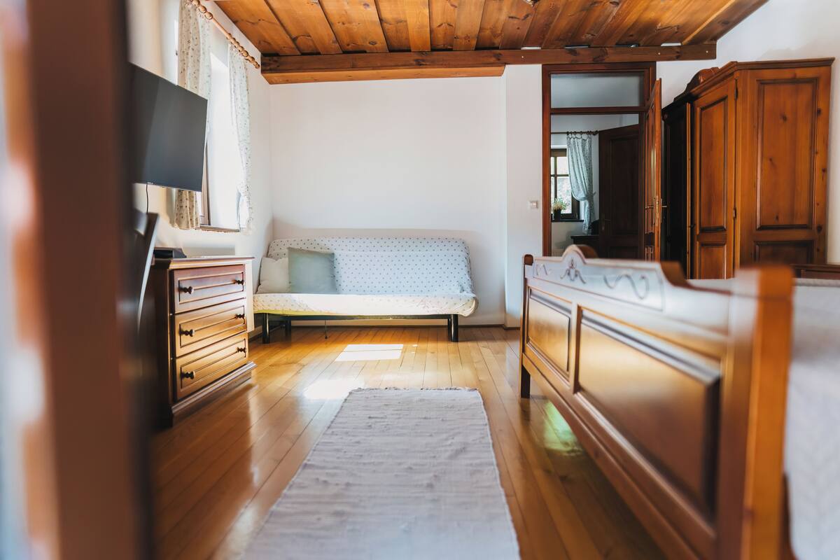 A room with a bed, wooden dresser, and a television.
