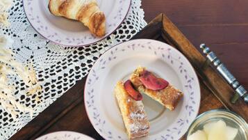 Un plateau avec un croissant, une part de gâteau aux fraises, une tasse de café et un verre d’eau.
