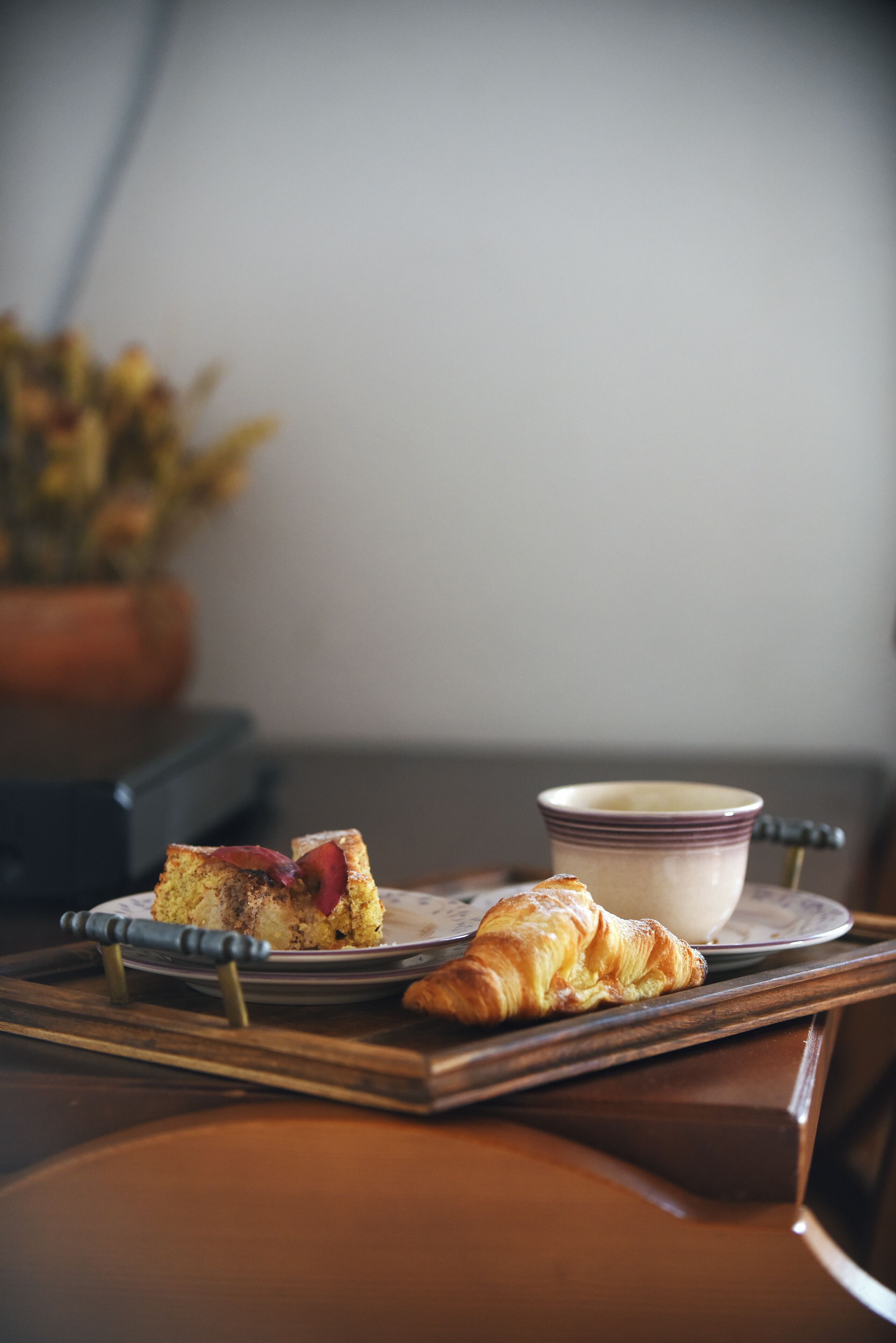 Una bandeja con una porción de pastel y un croissant sobre una mesa de madera.