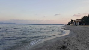 A beach with a sandy shore and a building with a sloped roof on the right.