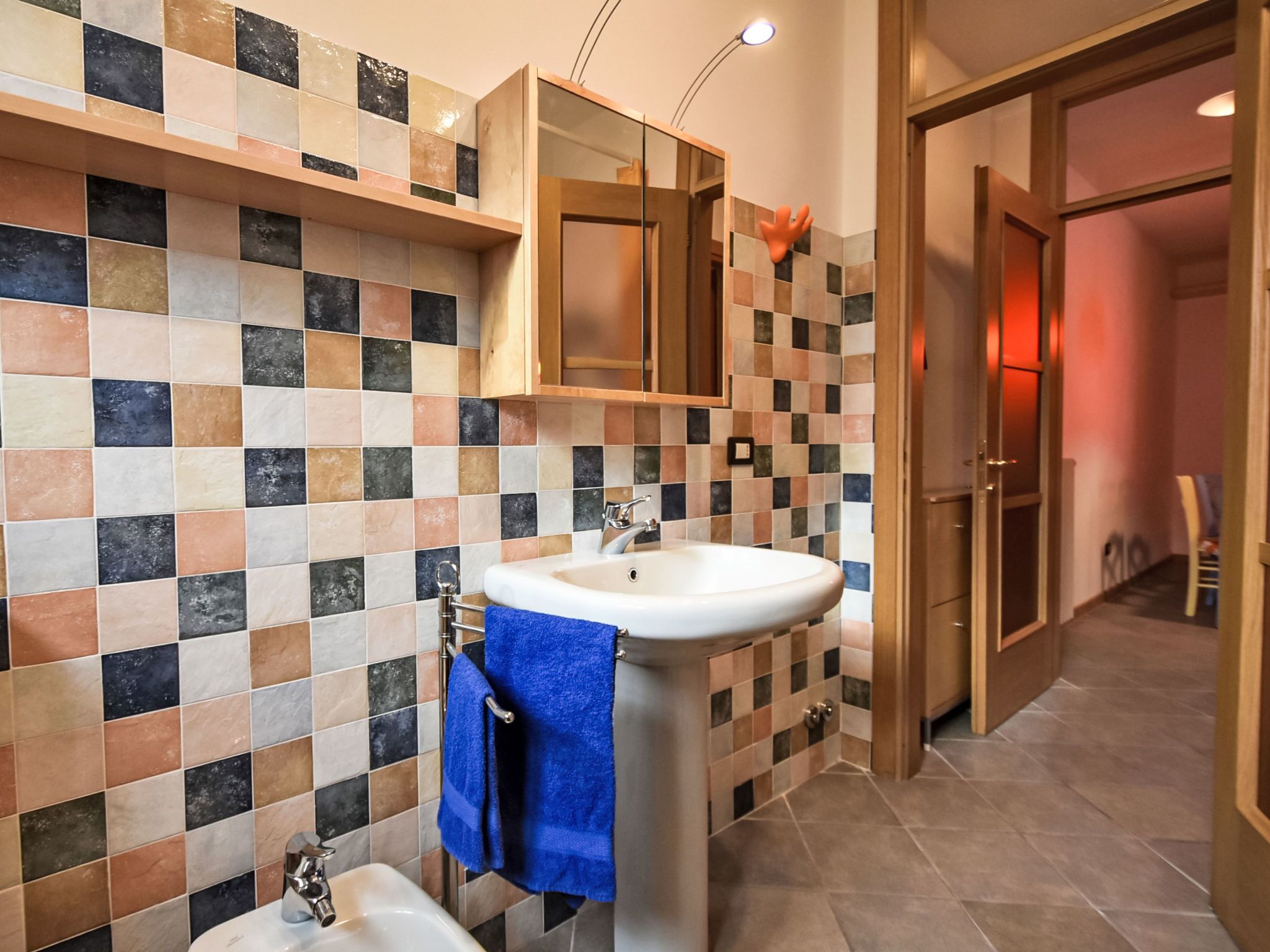 A bathroom with a tiled backsplash, a sink, a mirror, and a towel rack.