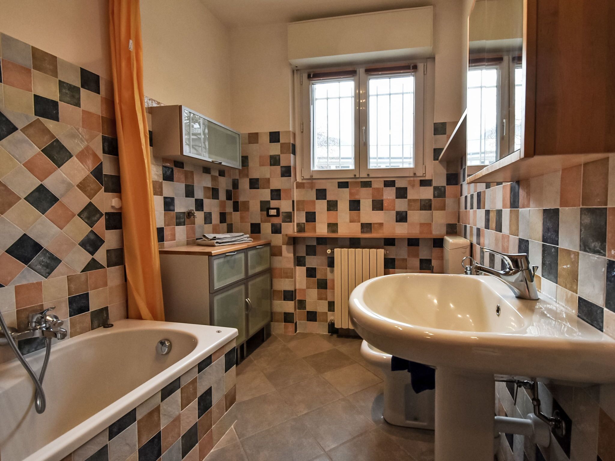 A bathroom with a tiled floor, a bathtub, a sink, and a window.