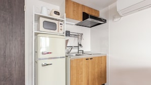 A compact kitchen with a microwave, refrigerator, and wooden cabinets. - CROWN Asakusabashi (Tokyo)