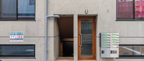 Un bâtiment avec une porte en bois, une enseigne et un coffret de raccordement.