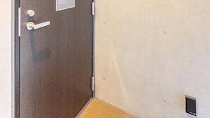 A hotel room with a wooden door, a small air conditioning unit, a wall-mounted intercom, and a door number sign. - CROWN Asakusabashi (Tokyo)