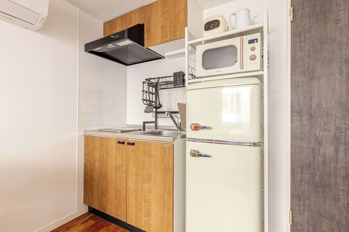 Una cocina compacta con microondas, refrigerador y armarios de madera.