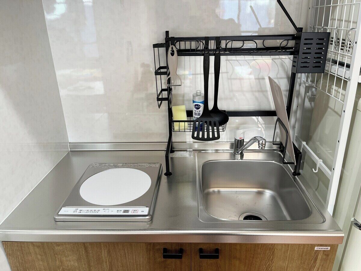 A compact kitchen with a built-in scale, a sink, and a utensil holder.
