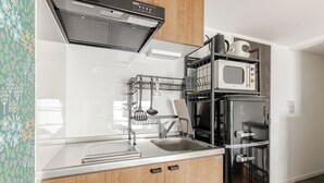 A modern kitchen with a stainless steel sink, a built-in microwave, and a black refrigerator. - CROWN Asakusabashi (Tokyo)