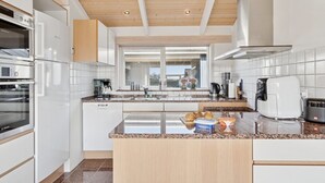 Une cuisine moderne avec des meubles blancs, un four Bosch, une machine à café et un grille-pain.