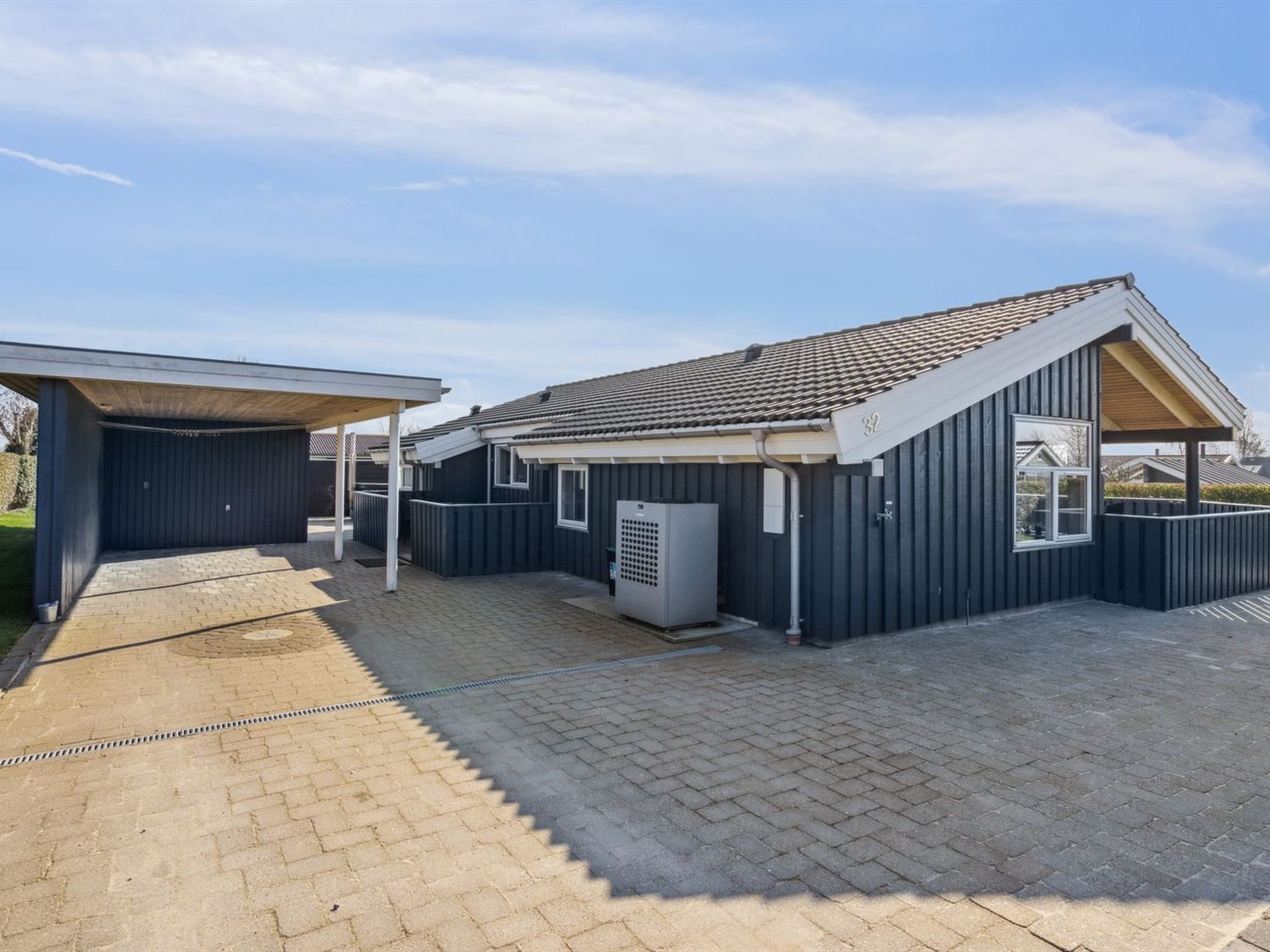 A modern house with a covered driveway and a fenced backyard.