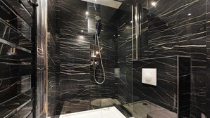 Une salle de bain moderne dotée d’une douche à parois de verre, d’une baignoire et de toilettes.
