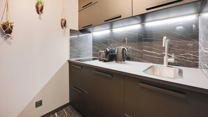 Une cuisine moderne avec un dosseret en marbre, des appareils en acier inoxydable et trois pots de fleurs suspendus.