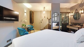 Une chambre d’hôtel moderne dotée d’un grand lit, d’un bureau avec une chaise, d’un téléviseur fixé au mur et d’une salle de bain avec un miroir et un lavabo.
