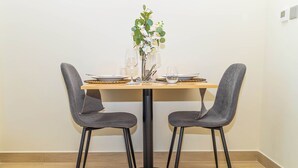 A dining table with two chairs, a vase with flowers, and a few glasses. - Bloomfields STU View Azizi Riviera (Dubai)