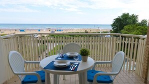 A balcony with a table set for two, overlooking a beach. - Apartment with panoramic view (Bibione)
