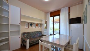 Una cocina compacta con mesa, sillas, sofá y refrigerador.