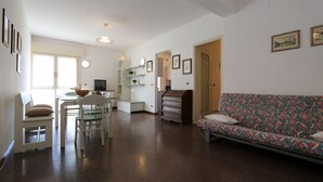 A spacious living area with a dining table, chairs, a sofa, and a TV. - Large house by the beach - Beahost (Bibione)