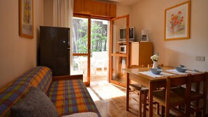 A cozy room with a sofa, a dining table with chairs, a TV, and a kitchen area with a microwave. - Lovely apartment with spacious terrace in Bibione (Bibione)