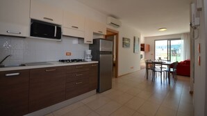Cuina moderna amb microones, nevera i fogó. Hi ha una zona de dinar amb taula i cadires.