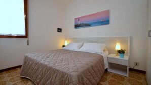 Un dormitorio con cama, mesitas de noche, un cuadro de un faro y alfombra estampada.