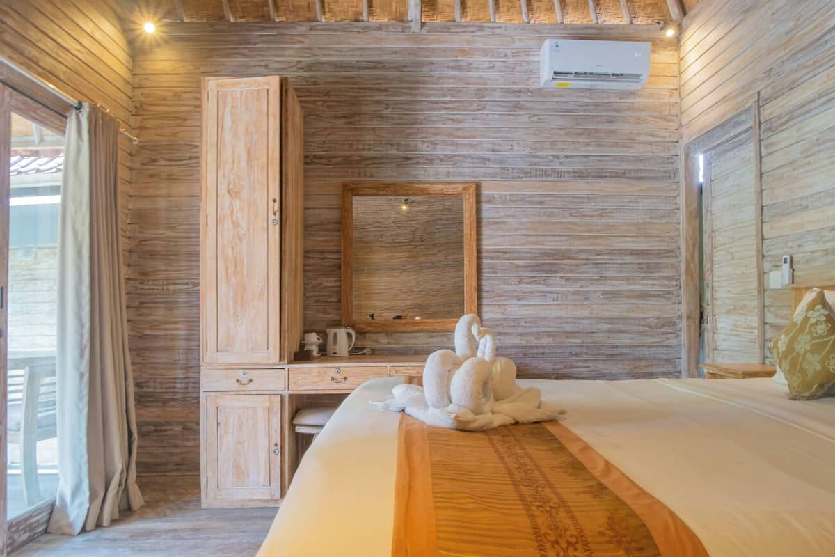 Una habitación con paneles de madera, una cama, un armario, un espejo y una ventana.