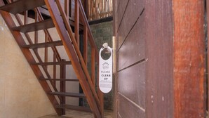 Una escalera de madera que lleva a una habitación con un cartel que solicita a los huéspedes limpiar.