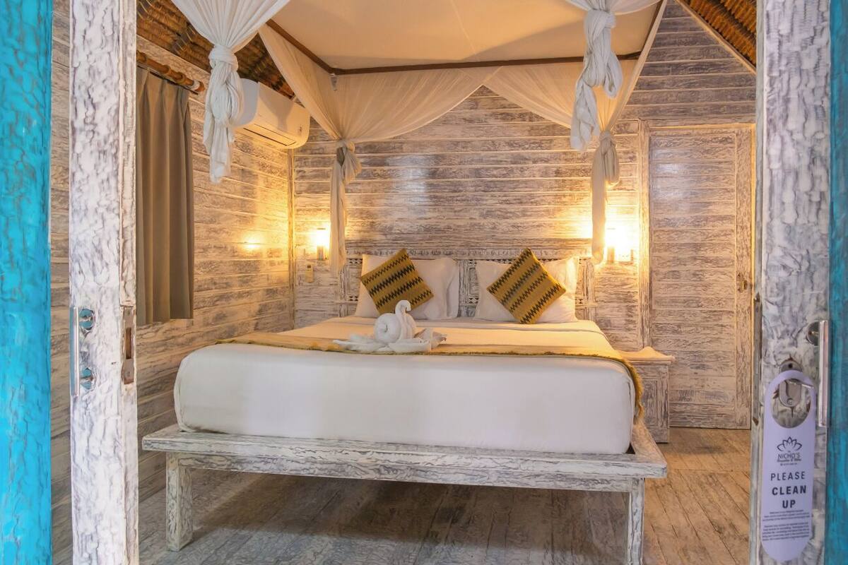 Un dormitorio con cama, mesitas de noche y dosel.
