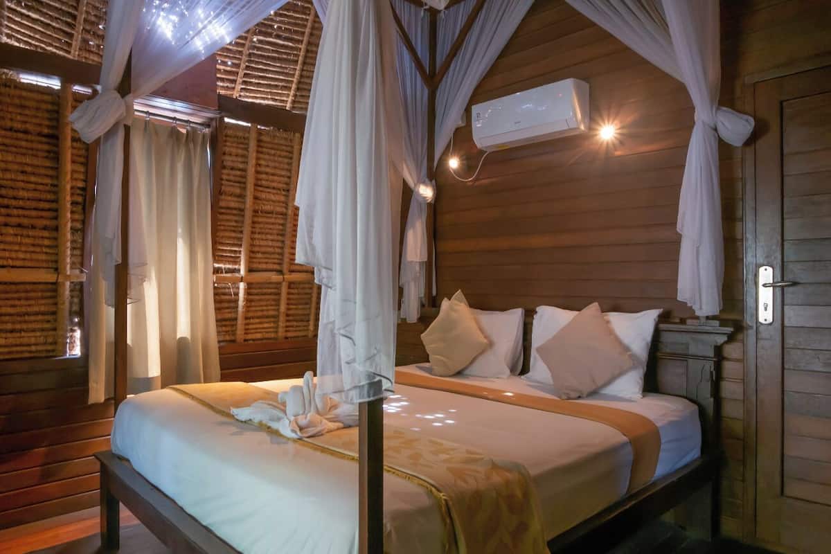 Una cama con dosel, paredes de madera y un equipo de aire acondicionado.
