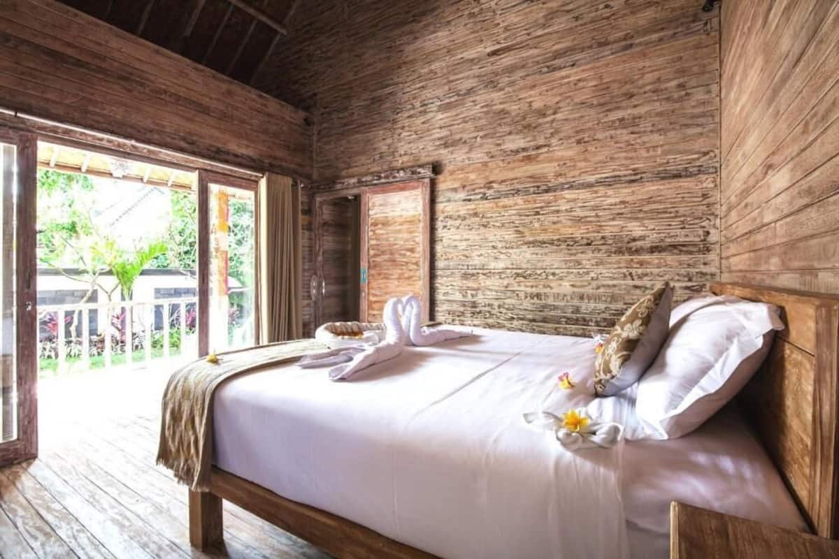 Una habitación de madera con cama, ventana y puerta.