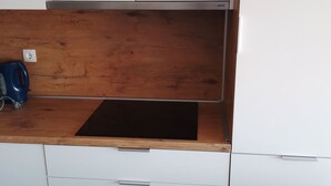 Una cocina con armarios blancos, encimera de madera y pileta negra.