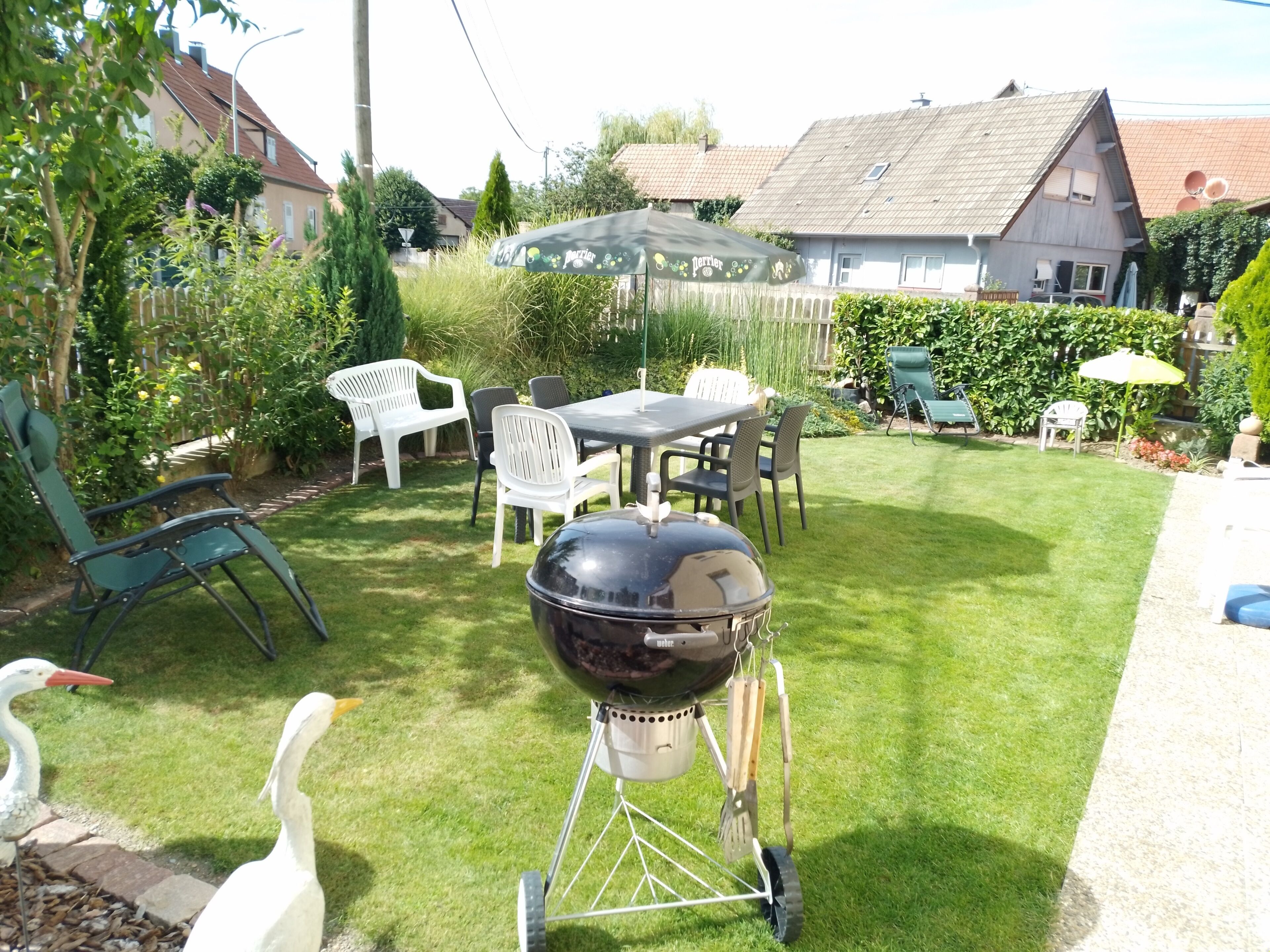 Un pati amb una barbacoa, mobles d'exterior i un jardí.