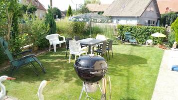 Un pati amb una barbacoa, mobles d'exterior i un jardí.