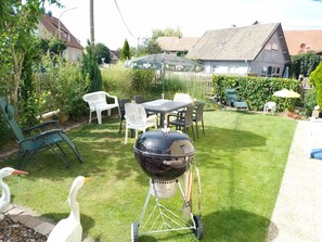 En baghave med grill, udendørs møbler og græsplæne.
