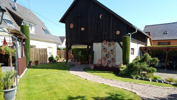 A traditional wooden building with a sloped roof, a well-maintained lawn, and a gravel path leading to the entrance.