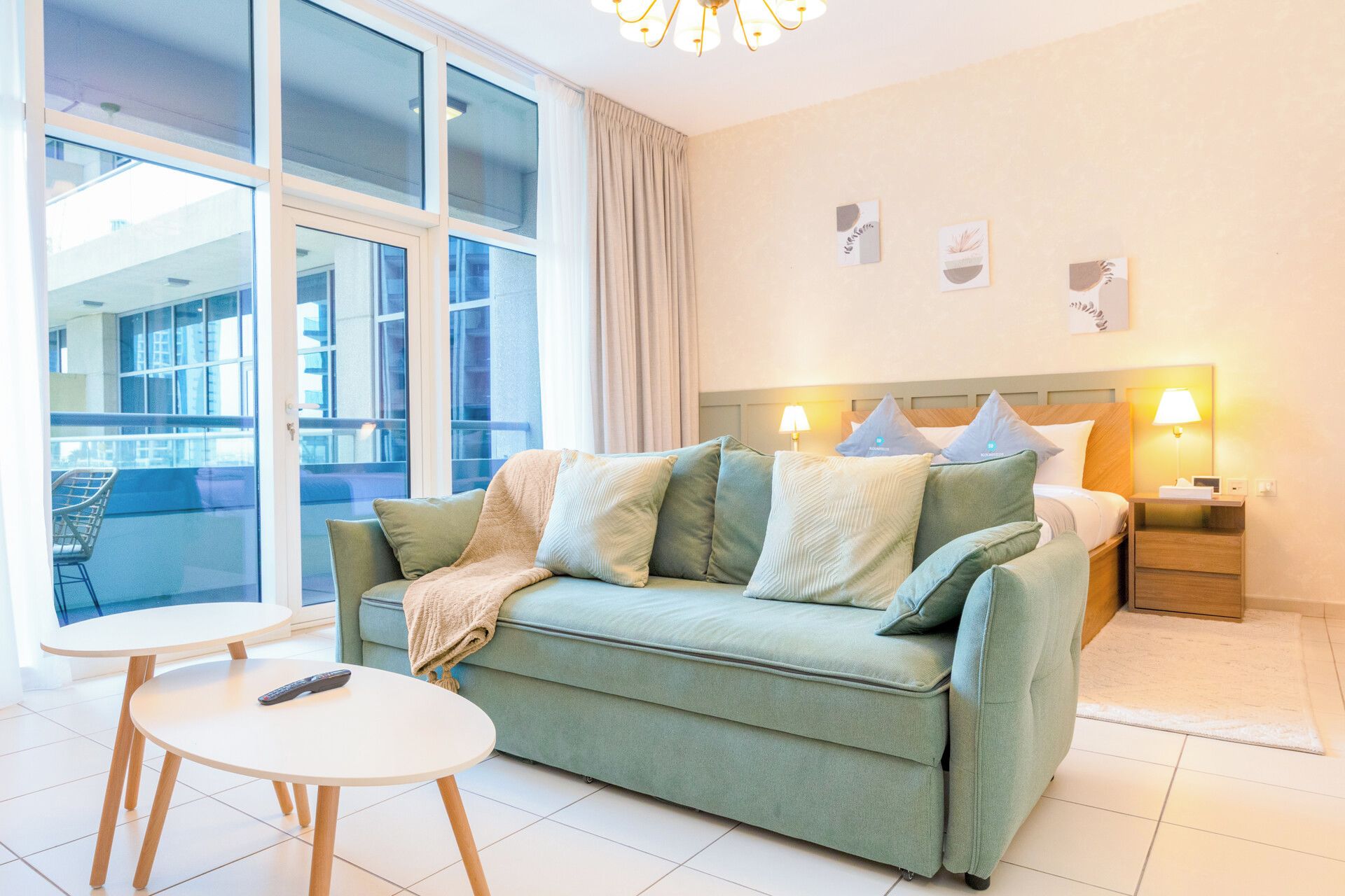 A modern hotel room with a sofa, bedside tables, and a view of the city.