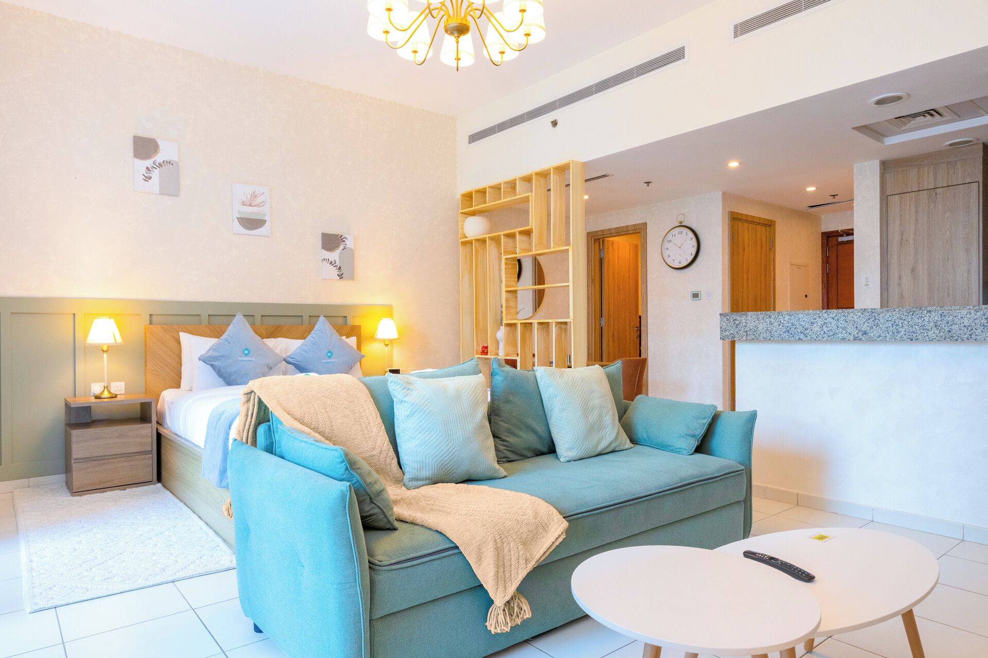 Una habitación de hotel con cama, sofá, una mesita y una pequeña cocina.