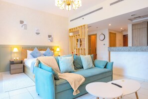 A hotel room with a bed, a sofa, a small table, and a kitchenette area.